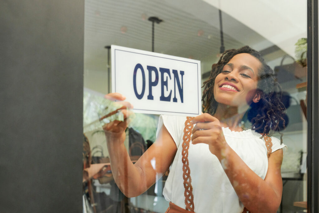 Small business owner putting up an open sign on her window